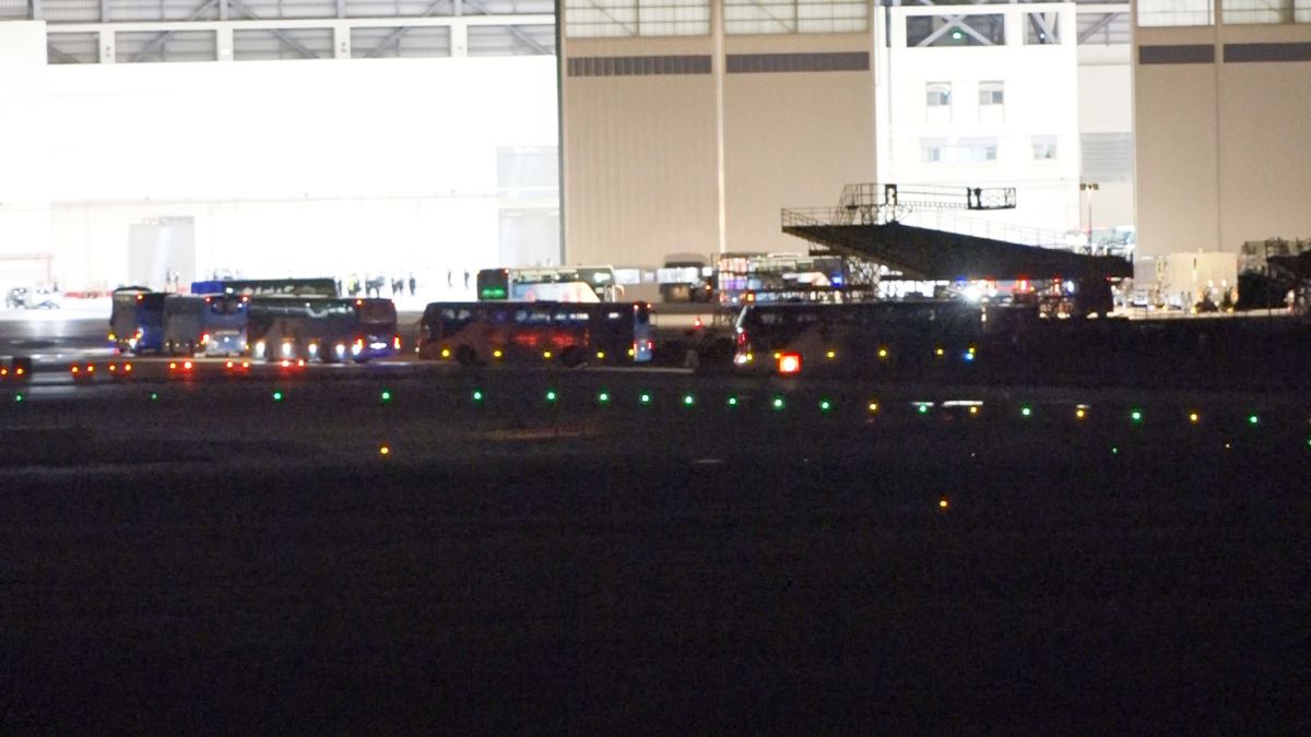 ▲載運返台旅客的遊覽車進入維修機棚，大批的檢疫人員也在現場嚴陣以待。（圖／記者林調遜攝, 2020.03.10）