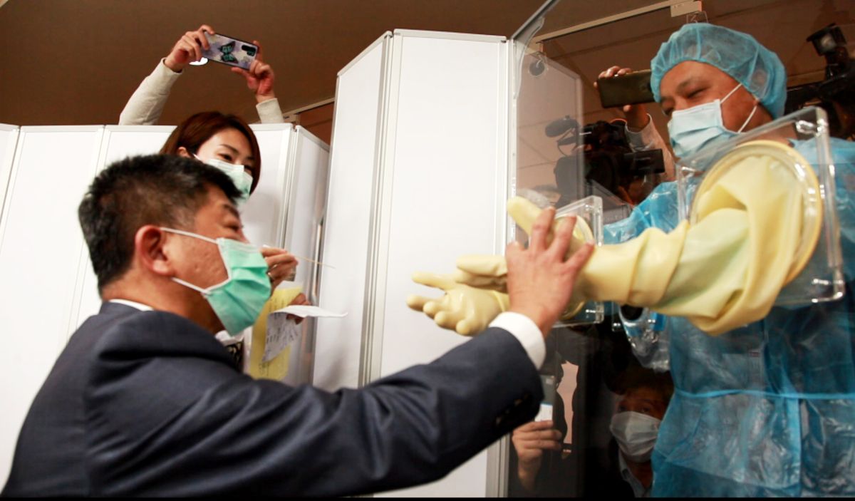 ▲坐在採檢位上，對檢查屏風的裝置相當好奇，一下子摸摸隔離採檢作業手套，一下子關心醫師採檢的距離夠不夠。（圖／記者李春台攝, 2020.03.27）