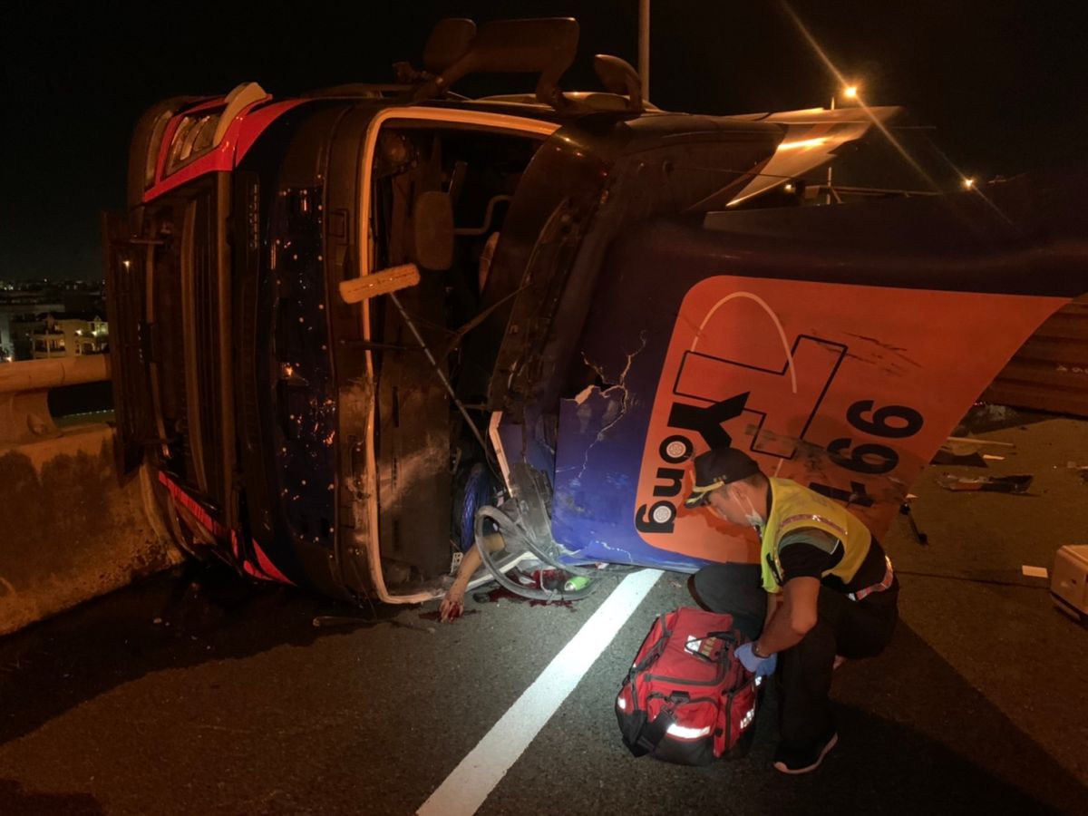 ▲國道三號接國道一號彰化系統交流道南下路段下坡彎道，一輛貨櫃車竟往左側翻，消防員動用破壞器材，將受困的駕駛救出送醫救治。（圖／記者陳雅芳翻攝，2020.06.21）