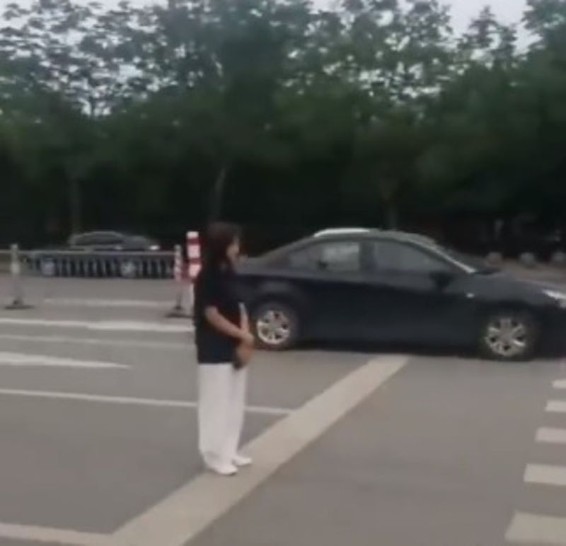▲一對新人在馬路上拍婚紗,工作人員站在路上用肉身擋車。(圖/翻攝自微博)