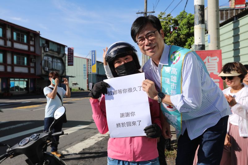 ▲民進黨高雄市長補選候選人陳其邁今（5）日在大樹區九大路與九曲路口站路口，熱情民眾特地拿著自己印的「故鄉等你很久了，謝謝你終於回來了」紙板，和陳其邁相見歡。（圖／陳其邁競選總部提供）