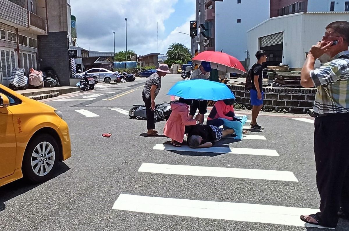 ▲澎湖馬公市區發生計程車與機車碰撞的意外，騎車老翁因受到驚嚇受傷無法起身，路過民眾拿出陽傘幫老翁遮陽，充分體現澎湖離島居民善良的一面。（圖／陳永富提供）