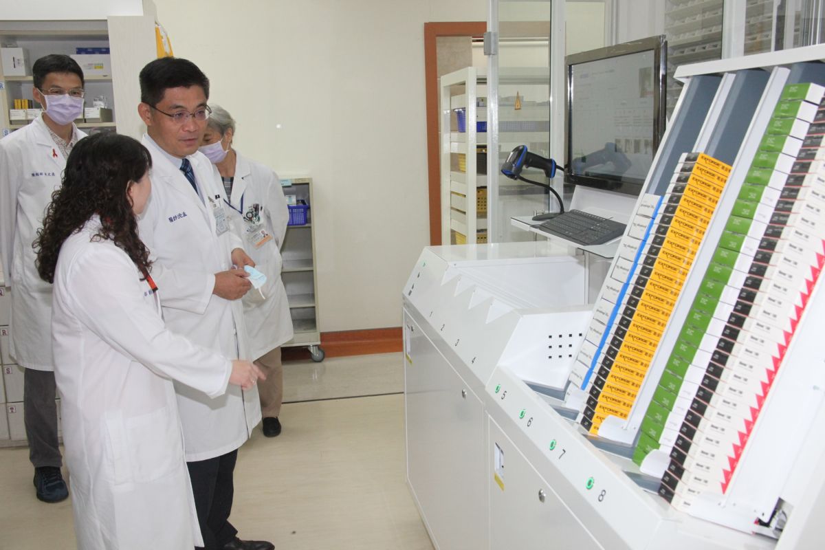 ▲藥劑部主任鄭靜蘭（左前一）向院長沈孟儒（左前二）說明盒裝調配機運作情形。（圖／成大醫院提供）