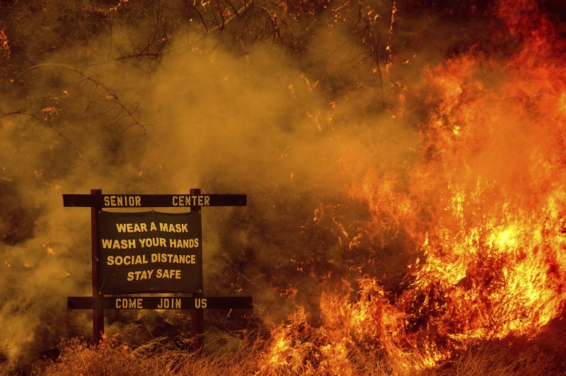 ▲這張由外媒記者於加州盛產葡萄酒而聞名的納帕郡（ Napa County ）拍攝到的照片，意外成為美國網友的話題，因為照片顯示快被野火燒掉的告示板上，寫着「戴口罩、勤洗手，保持社交距離、注意安全」等防疫字句，為當前加州多災多難，遭受疫情和野火夾擊的困境下了最好的詮釋。（圖／美聯社／達志影像）