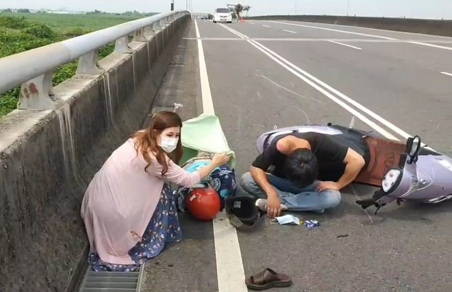 ▲美麗而熱心的絲巾姐見到車禍傷者，除將自己的白色車子擋在30公尺外，並蹲下身子為傷者遮陽，安撫傷者。(圖／讀者翁先生提供）