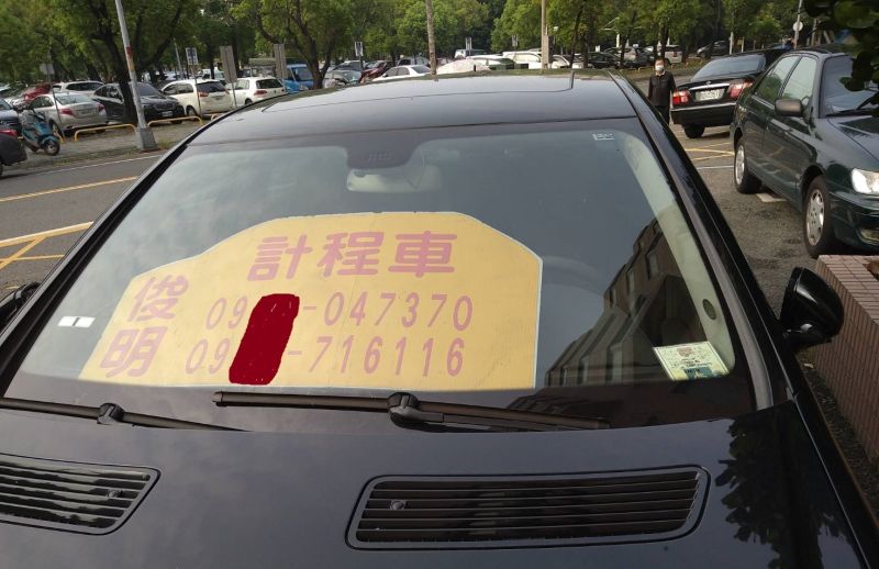 ▲車主在前擋風玻璃置放一塊黃色底色寫著「俊明計程車」和連絡電話。（圖／記者簡勇鵬攝，2020.09.11）