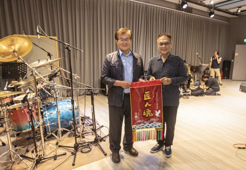 ▲鼓王黃瑞豐獲頒今年金曲獎的「特別貢獻獎」,文化總會推出《匠人魂》#26「海上的人」影片,記錄他的打鼓生涯。文總副會長江春男也致贈黃瑞豐一面《匠人魂》錦旗。(圖/文總提供)