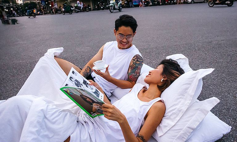 ▲一對來自越南的情侶屏棄唯美的裝飾佈景，選擇把枕頭和棉被搬到街上，拍攝出一系列在街上共眠的奇特婚紗照。（圖／翻攝自臉書）