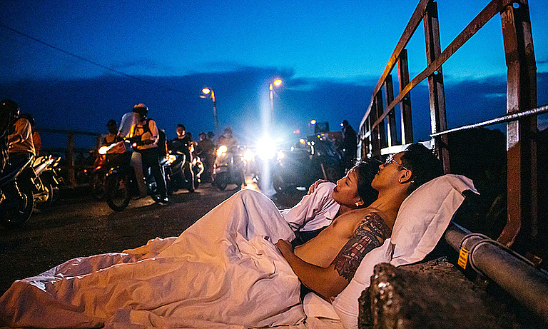 ▲一對來自越南的情侶屏棄唯美的裝飾佈景，選擇把枕頭和棉被搬到街上，拍攝出一系列在街上共眠的奇特婚紗照。（圖／翻攝自臉書）