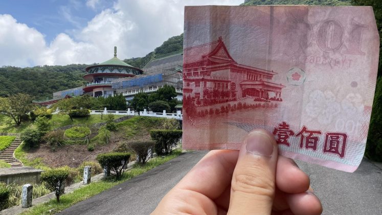 ▲The Reddit user, nicknamed @IB-45, holds a half-folded NT$100 Taiwanese bill, which perfectly aligns with the building in the background, leading many to question whether the picture is real. （Courtesy of @IB-45/Reddit)