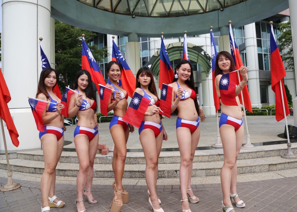 ▲身著國旗泳裝的年輕女孩，手持中華民國生日快樂手板，站在議會噴泉廣場，熱情歡迎全國民眾，不分藍綠一起來台南歡度國慶看焰火。（圖／台南市議會國民黨團提供）