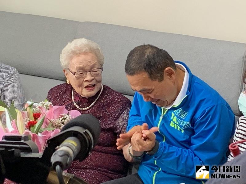 ▲侯友宜撫摸著阿嬤的手，直說「幼綿綿」，阿嬤笑說現在不用做家事了啊。(圖/記者康子仁攝)