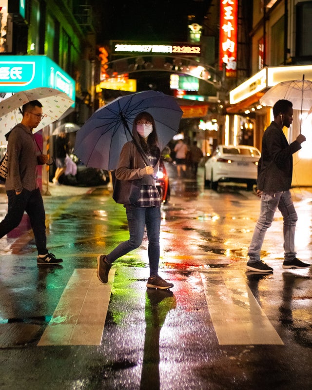 ▲路人手持雨傘穿越斑馬線 | The photo shows the three walking through the pedestrians crossing in Taipei. (Courtesy of Nial Stewart)