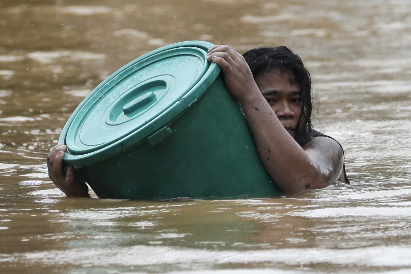 ▲颱風梵高重創菲律賓，已釀至少 27 人死亡，數十萬人流離失所。圖為抱水桶漂浮逃生的民眾。（圖／美聯社／達志影像）