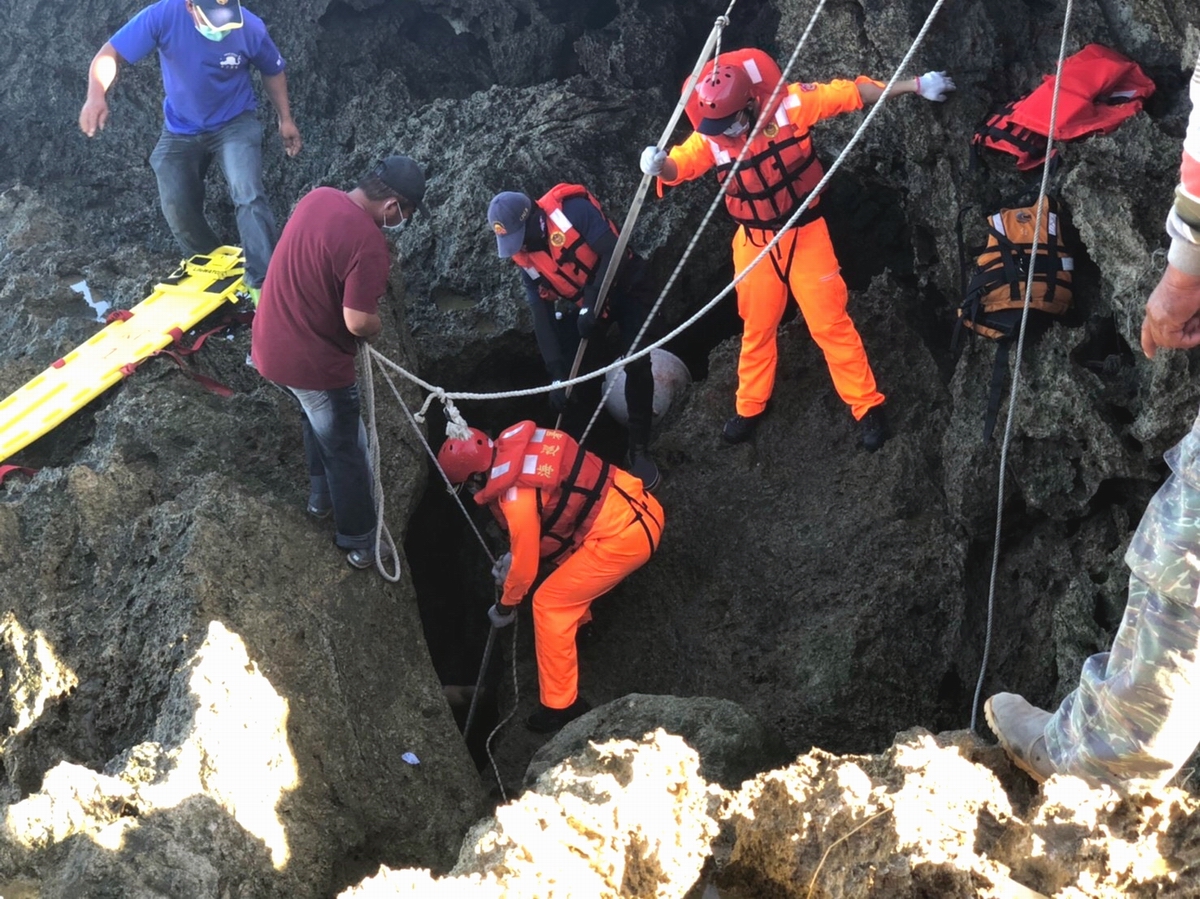 ▲採捕海菜失足落海吳姓民眾在龍坑岸際礁岩縫隙中發現，空間狹小海巡同仁及消防人員運用長背板固定及繩索吊掛共同協助下將遺體搬運出岸際。（圖／記者黃正忠翻攝, 2020.11.23）