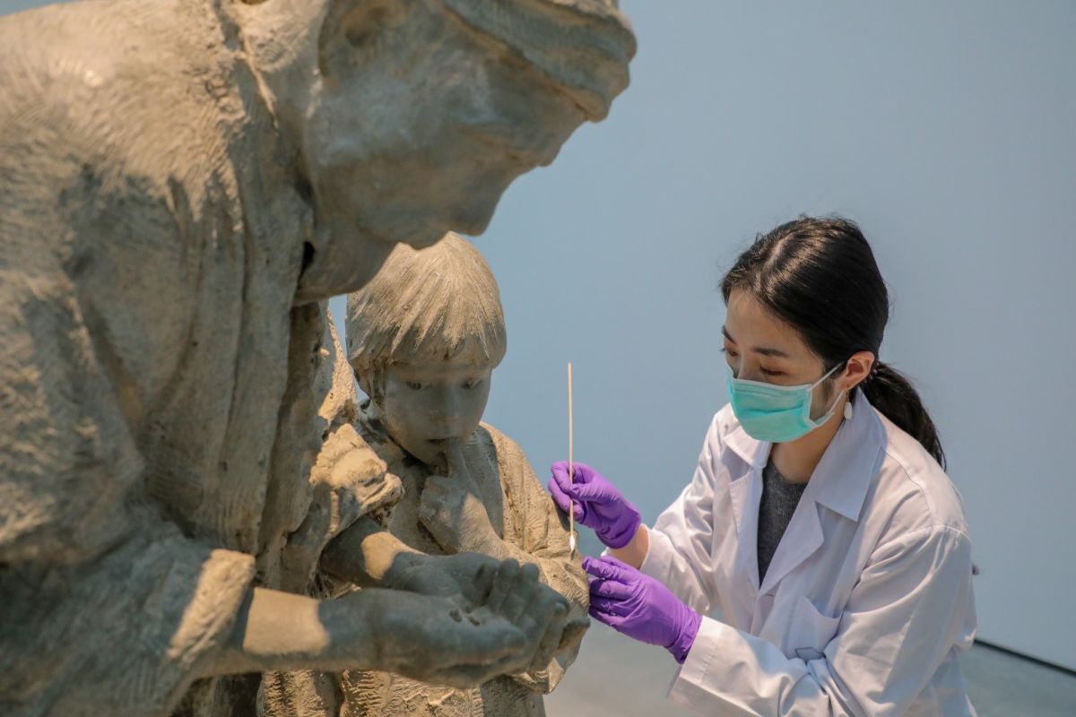 ▲圖中修復師正仔細幫侯金水雕塑作品「難民系列」淡化污漬。（圖／記者林怡孜攝，2020,12,10）