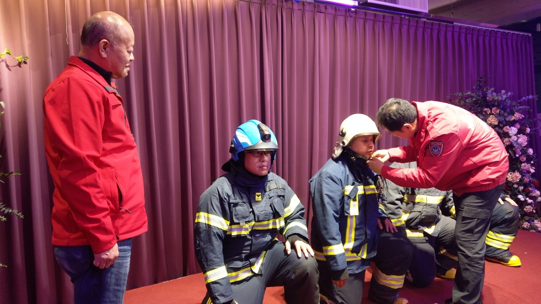 ▲嘉義縣首創師徒制授業儀式，新進義消人員一字排開，由義消總隊總隊長張明達和師傅們幫徒弟「戴上消防帽，上扣環」，象徵將無私傳承消防經驗。(圖／嘉義縣消防局提供）