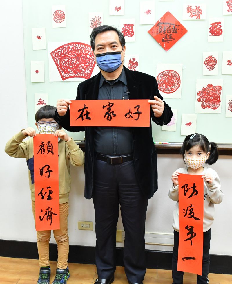 ▲寫得一手好書法的政委羅秉成,和小朋友一起寫春聯。(圖/行政院提供)