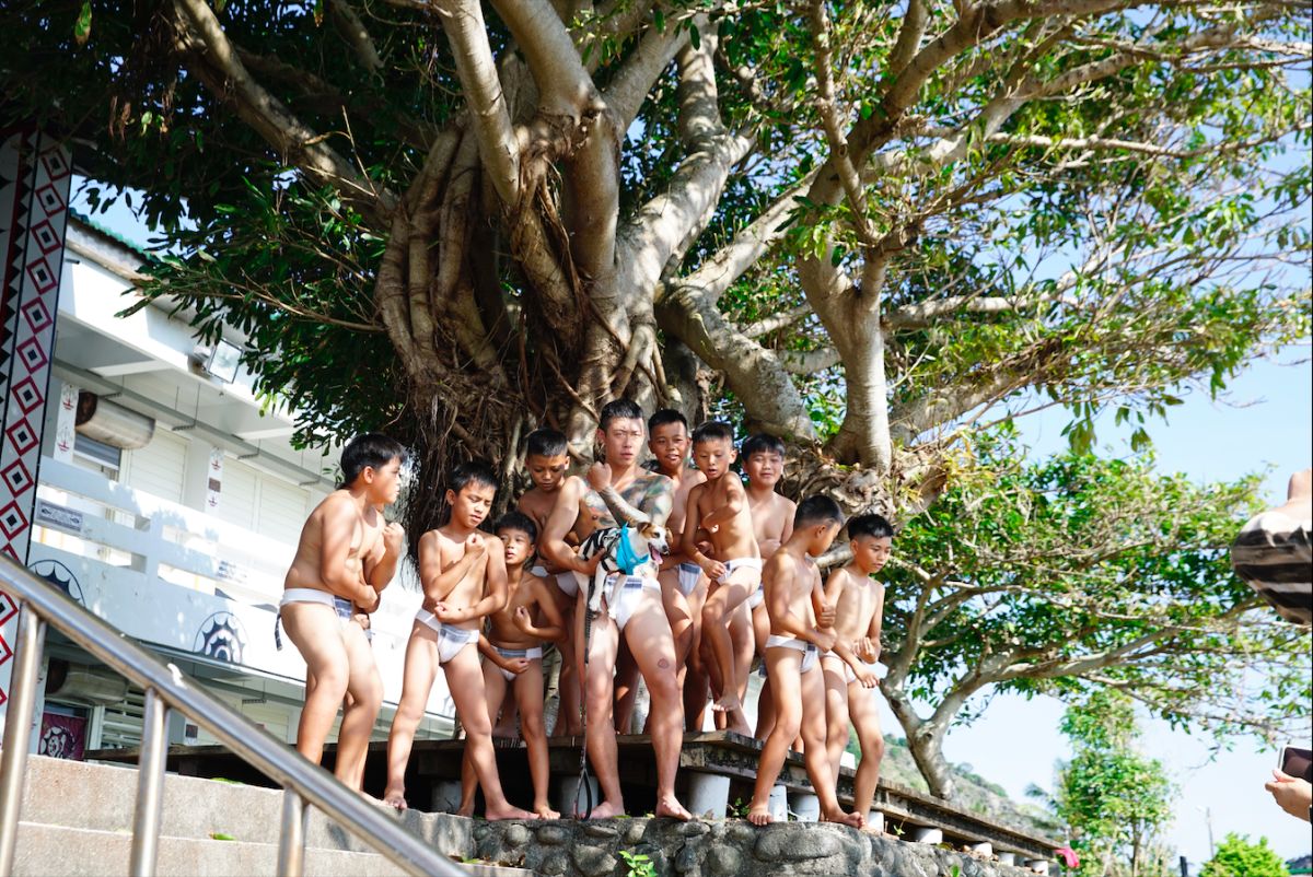 ▲玖壹壹健志（前排中）換上丁字褲學習達悟族的勇士舞，害羞表示事前沒「淨身」。（圖／混血兒娛樂提供）