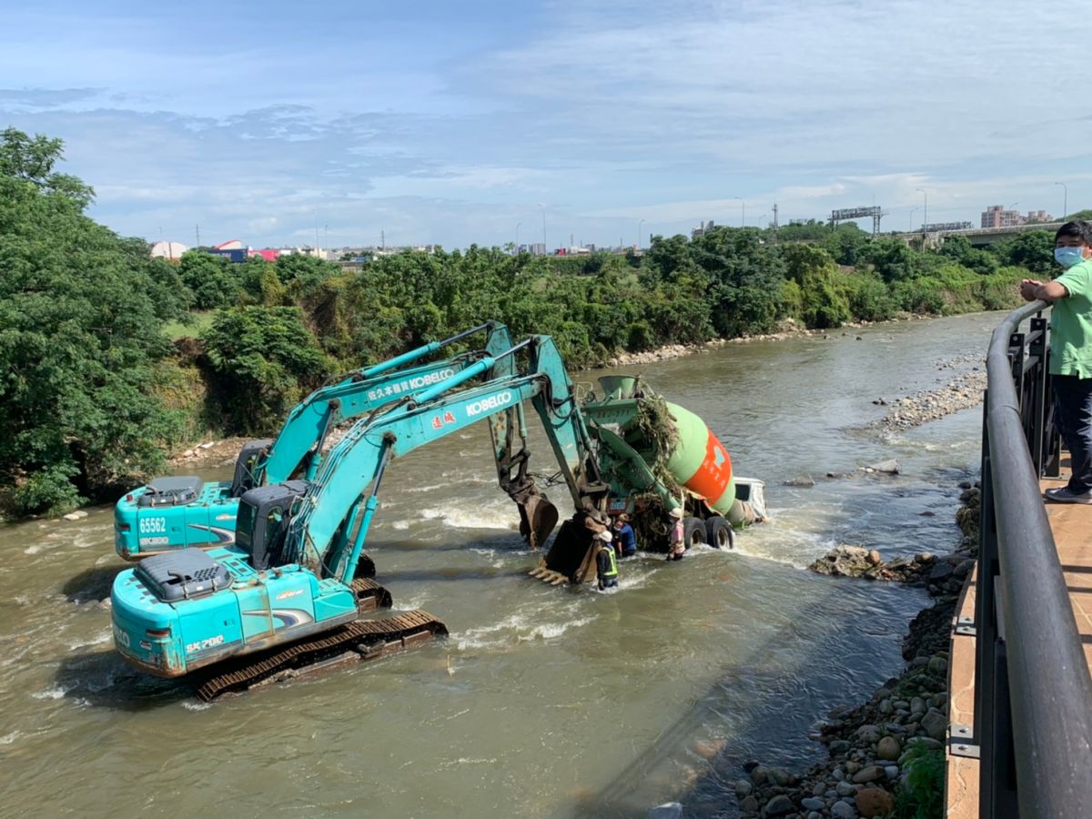 ▲大雨造成中壢新街溪水暴漲，竟沖走施工中的一輛混凝土預拌車。圖為兩輛怪手正進行打撈作業。（圖／中壢警方提供）
