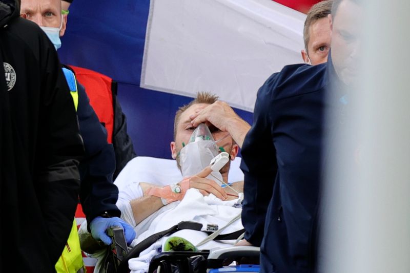 ▲丹麥球星Christian Eriksen在比賽中突然昏倒，擔架抬下場時，對手芬蘭球迷暖心遞上手中國旗為Eriksen遮擋。（圖／美聯社／達志影像）