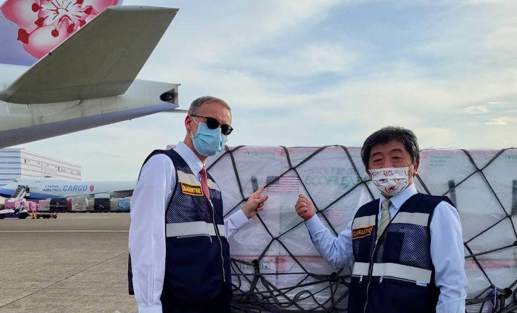 ▲衛生福利部部長陳時中（右）及美國在台協會台北辦事處處長酈英傑（Brent Christensen)（左）至桃園機場迎接美國援贈我國之250萬劑莫德納（Moderna）疫苗。(圖／外交部提供)