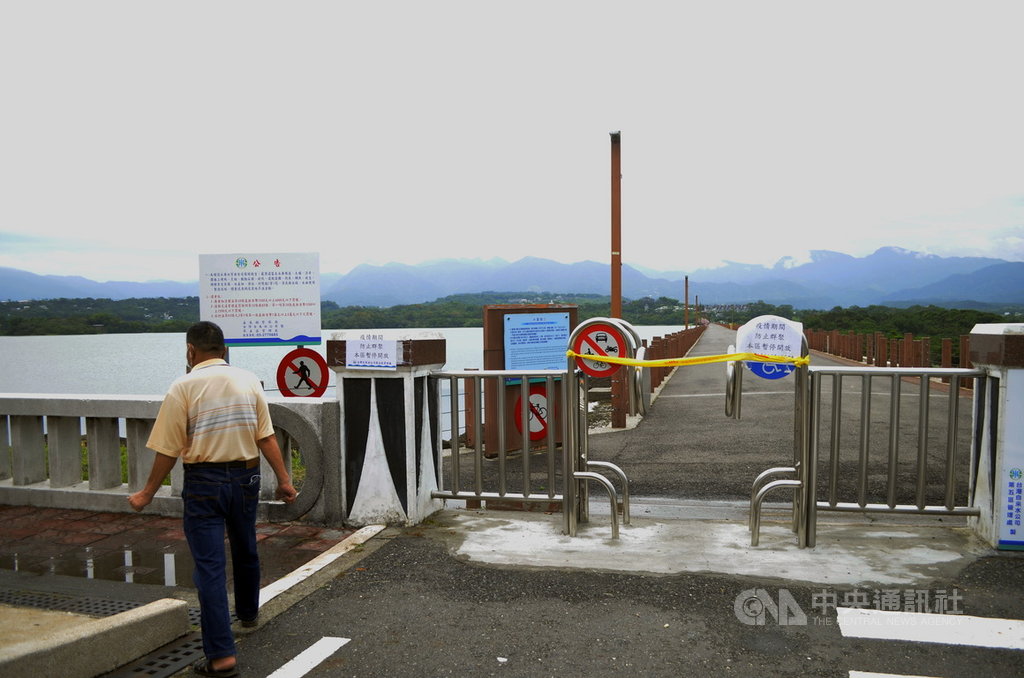 ▲疫情3級警戒，嘉義縣仁義潭水庫大壩假日卻出現散步人潮，自來水公司派人在大壩兩側的出入口，貼上告示「疫情期間，防止群聚，本區暫停開放」。（圖/中央社）
