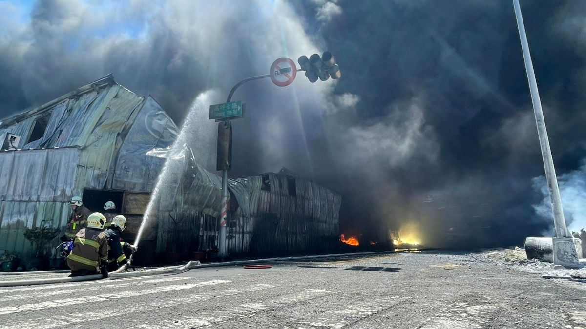 ▲小港區高坪七路上冠敏企業戶外堆置的鎂合金燃燒，消防員針對周邊廠房加強射水防護。（圖／翻攝畫面）