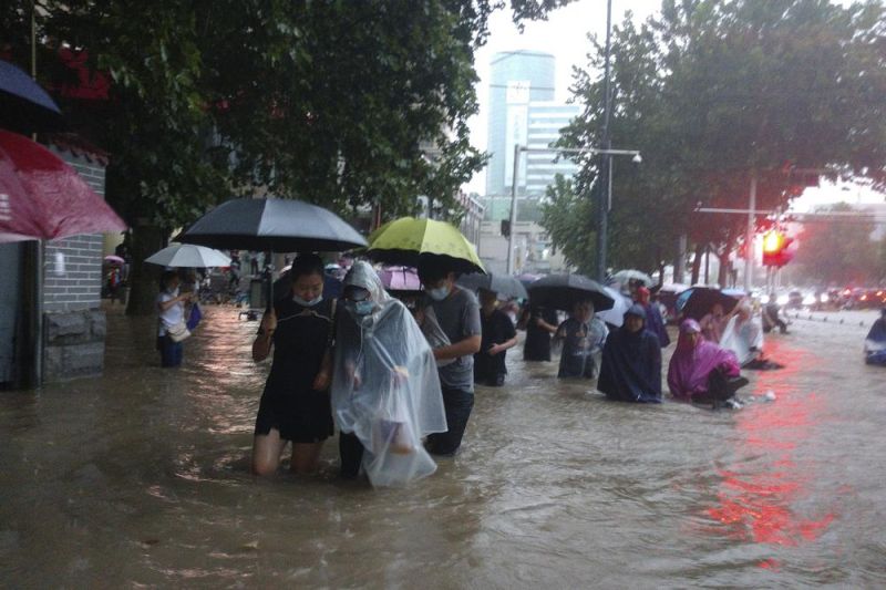 ▲中國河南省鄭州遭到大雨襲擊，街道變成河道，民眾冒險涉水行走。（圖／美聯社／達志影像）