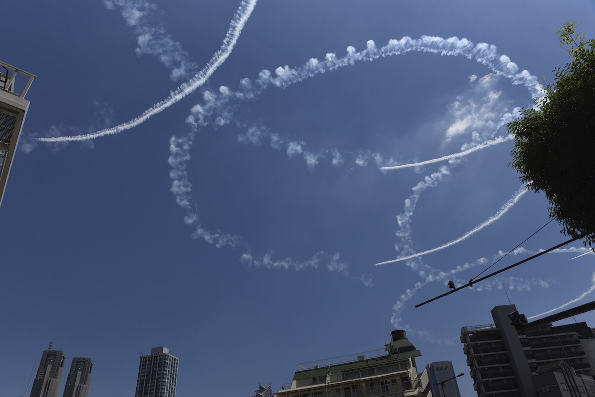 ▲東京奧運23日開幕，日本航空自衛隊將出動飛行表演隊「藍色衝擊波」在東京上空、尤其是東奧主場館國立競技場上方飛航，畫出五彩五環模樣，今天先進行畫白煙預演，吸引許多飛機迷拍攝。（圖／美聯社／達志影像）