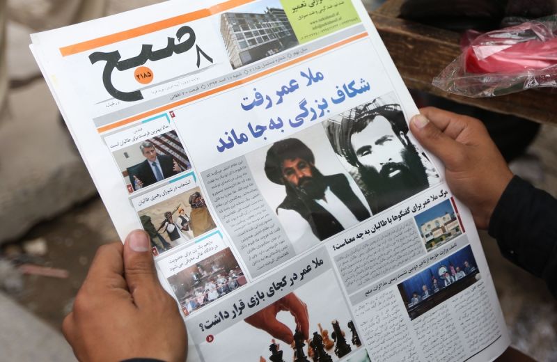 ▲阿富汗民眾觀看報紙上神學士領導人更迭的新聞。右側黑白照片為創辦人歐瑪。（圖／美聯社／達志影像）