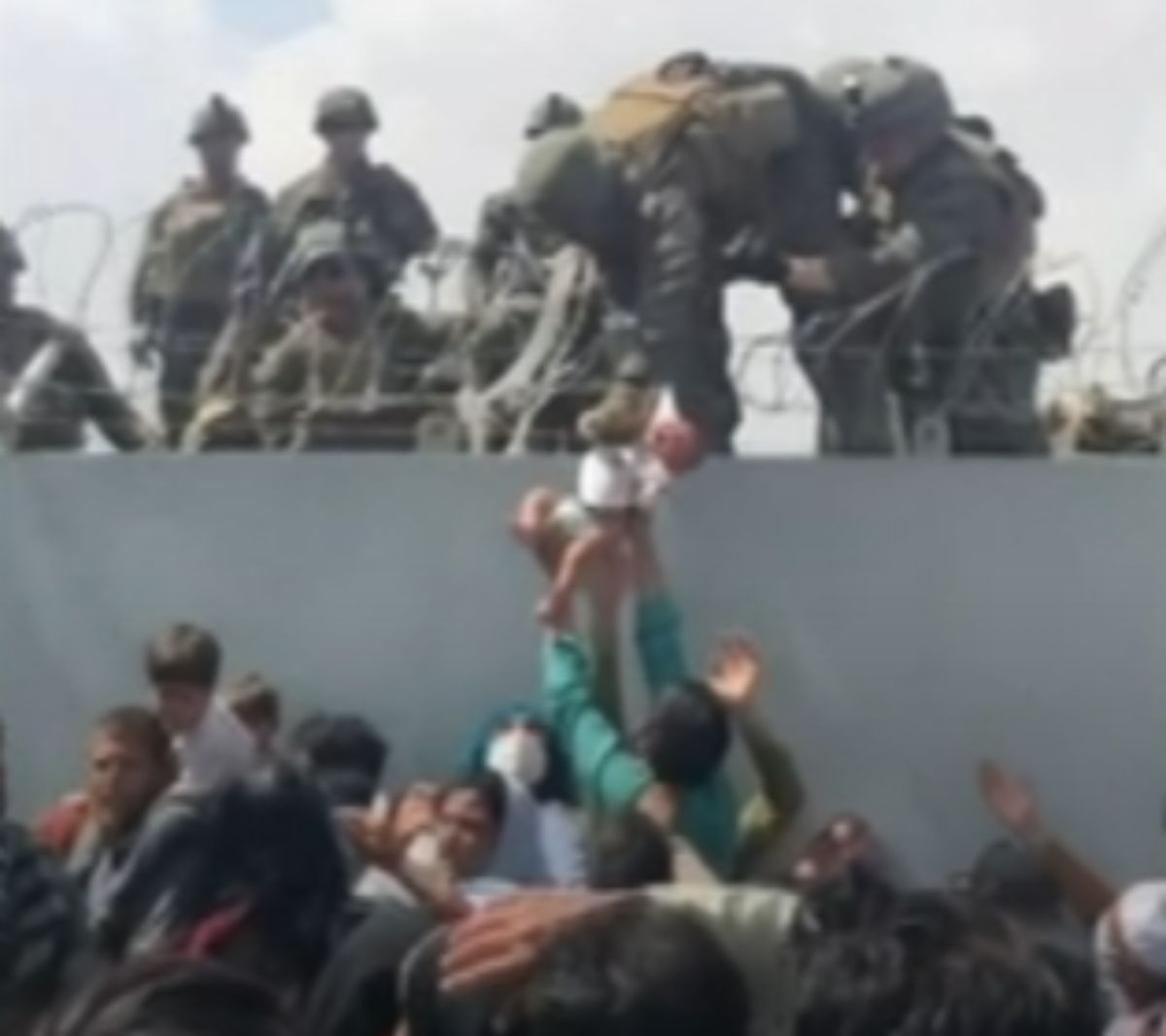 ▲武裝組織塔利班掌控阿富汗後，許多人奔赴喀布爾機場試圖逃離。在混亂中，一支感人的影片在網路瘋傳，內容顯示美軍陸戰隊員從高處將包著尿布的嬰兒拎過裝有刺網的圍牆。（圖／擷取自影片）