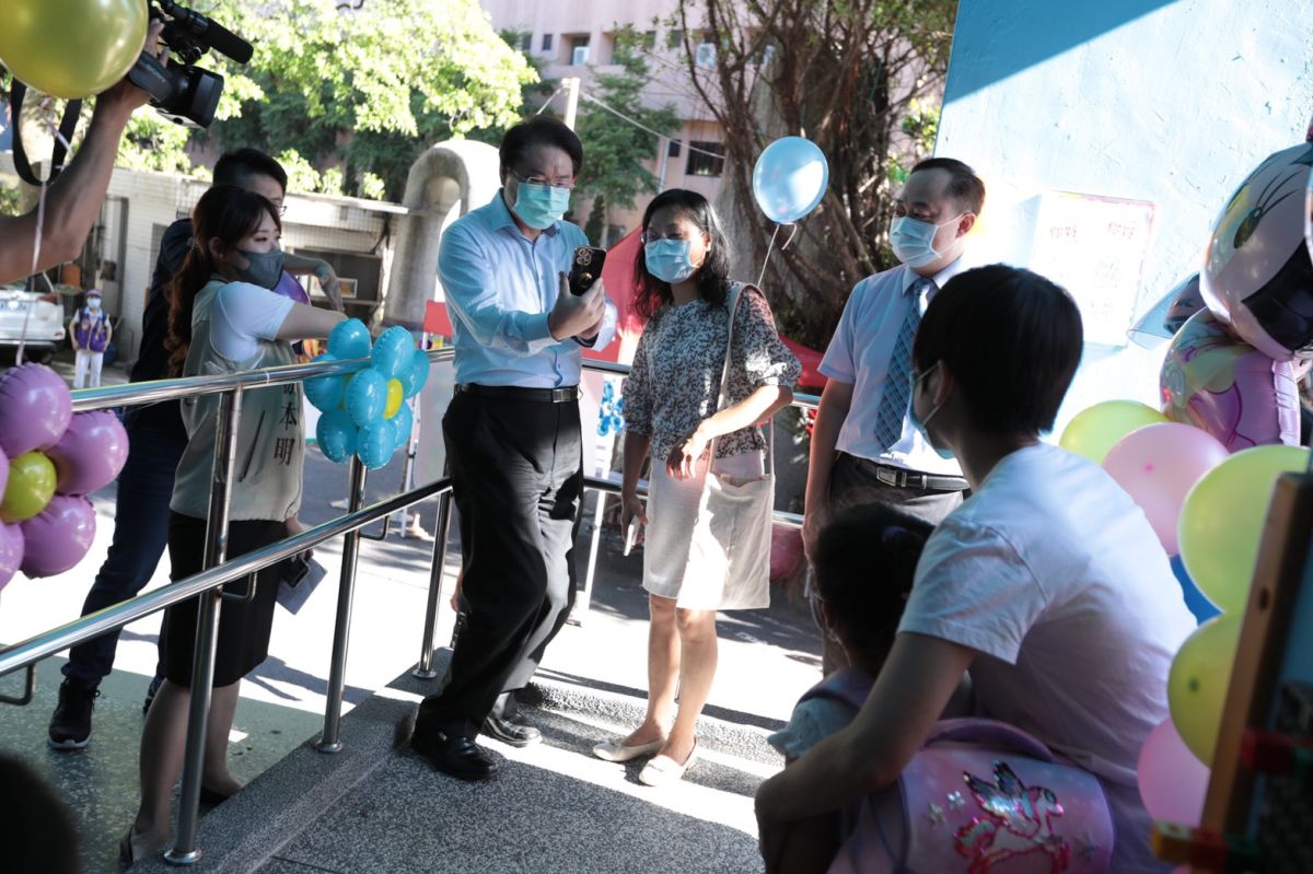 ▲基隆市長林右昌還很「順手」地幫前面的家長接過手機，記錄小一新生及家長們一起排隊進入校園這一刻。（圖／基隆市政府提供）