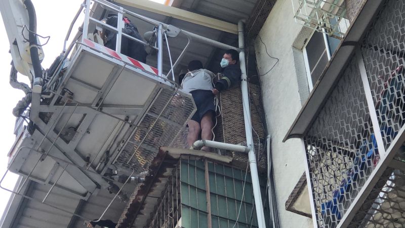▲男子受困圍牆外，消防隊趕緊操作雲梯車升梯將人救下。（圖／翻攝畫面）