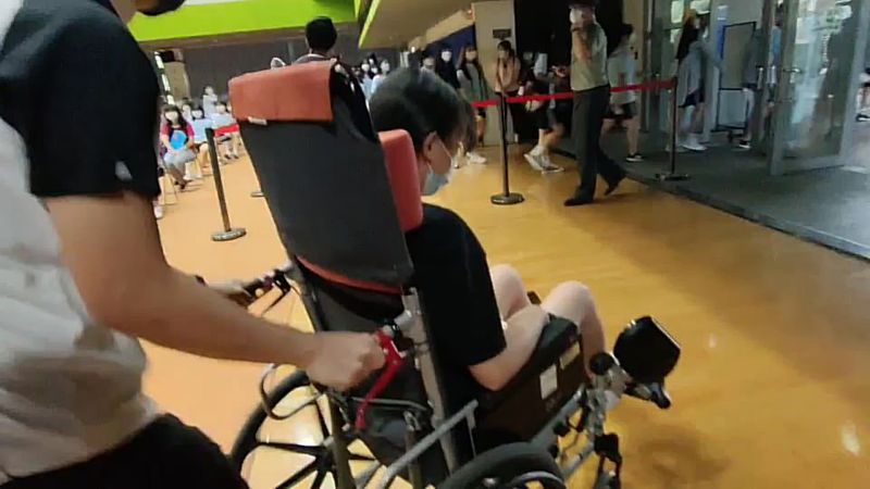 ▲大園高中今天有19位同學出現暈針的狀況,由護理人員以輪椅送至休息區休息。(圖/記者李春台翻攝)