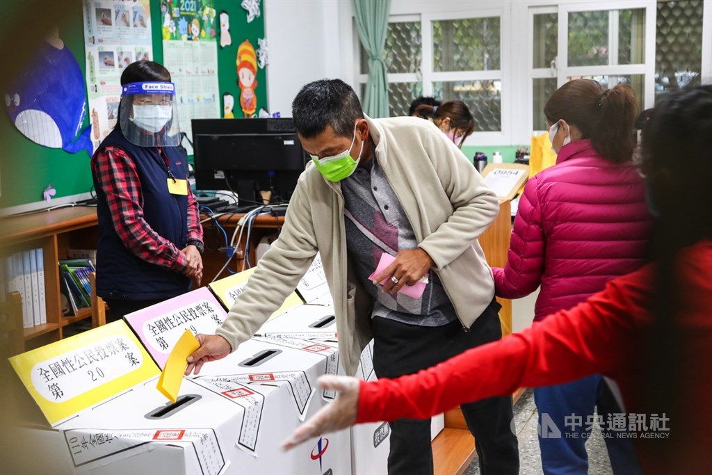 ▲重啟核四、反萊豬、公投綁大選及三接遷離公投案18日投票，投票所選務人員配合防疫穿戴防護面罩及手套等裝備，現場引導民眾投票，讓動線更流暢。中央社記者王騰毅攝 110年12月18日