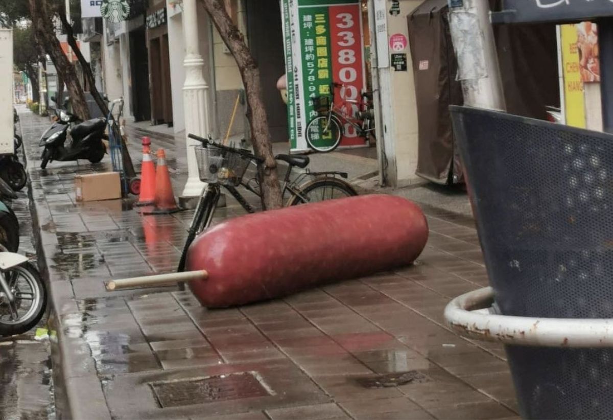 ▲高雄一名網友在網路上貼出照片，裡頭有一支超巨大香腸躺在人行道中間，讓畫面看起來十分怪異。（圖／翻攝自「爆廢公社二館」）
