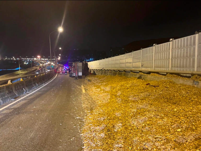 ▲台64線快速道路，一輛曳引車自撞護欄翻覆，車上木屑散落滿地。（圖／翻攝畫面）