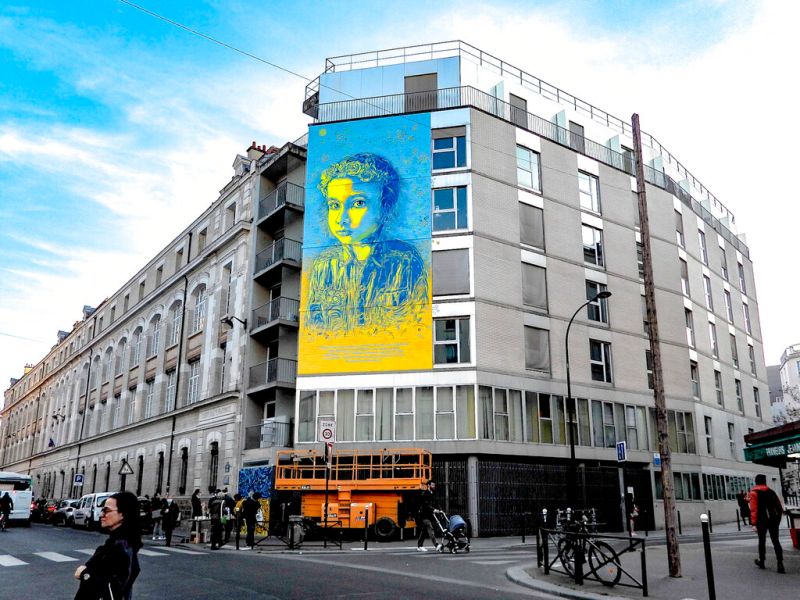 ▲法國街頭藝術家C215懸掛巨大的藍黃色調烏克蘭女孩肖像畫，提醒世人俄羅斯對烏克蘭發動戰爭所造成的人命代價。（圖／美聯社）