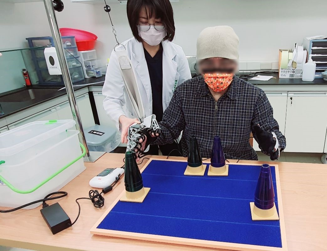 ▲職能治療師引導患者使用智慧鏡像機器手的輔助進行手部上肢復健訓練活動。（圖／新竹臺大分院生醫醫院提供）