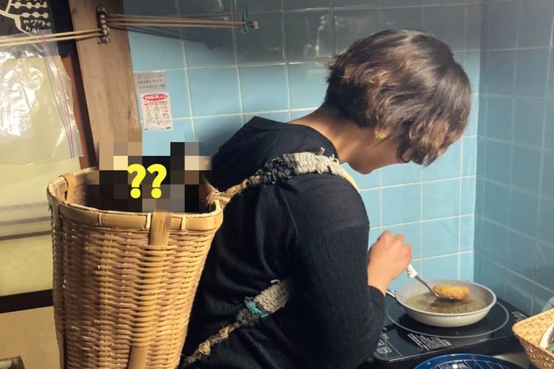 ▲日本一名主婦一邊揹著「寶寶」一邊忙烹飪。（圖／推特帳號1Shuo）