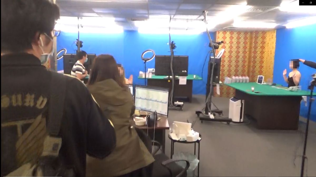 ▲警方攻堅賭場時，穿著低胸女荷管嚇得高舉雙手「投降」（圖/記者鄧力軍翻攝）