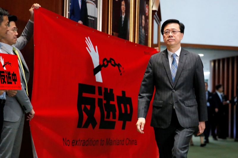 ▲香港前政務司司長李家超成為2022年香港特首選舉的唯一候選人。圖為2019年反送中期間，李家超從手持抗議標語的民主派議員面前走過。（圖／美聯社／達志影像）