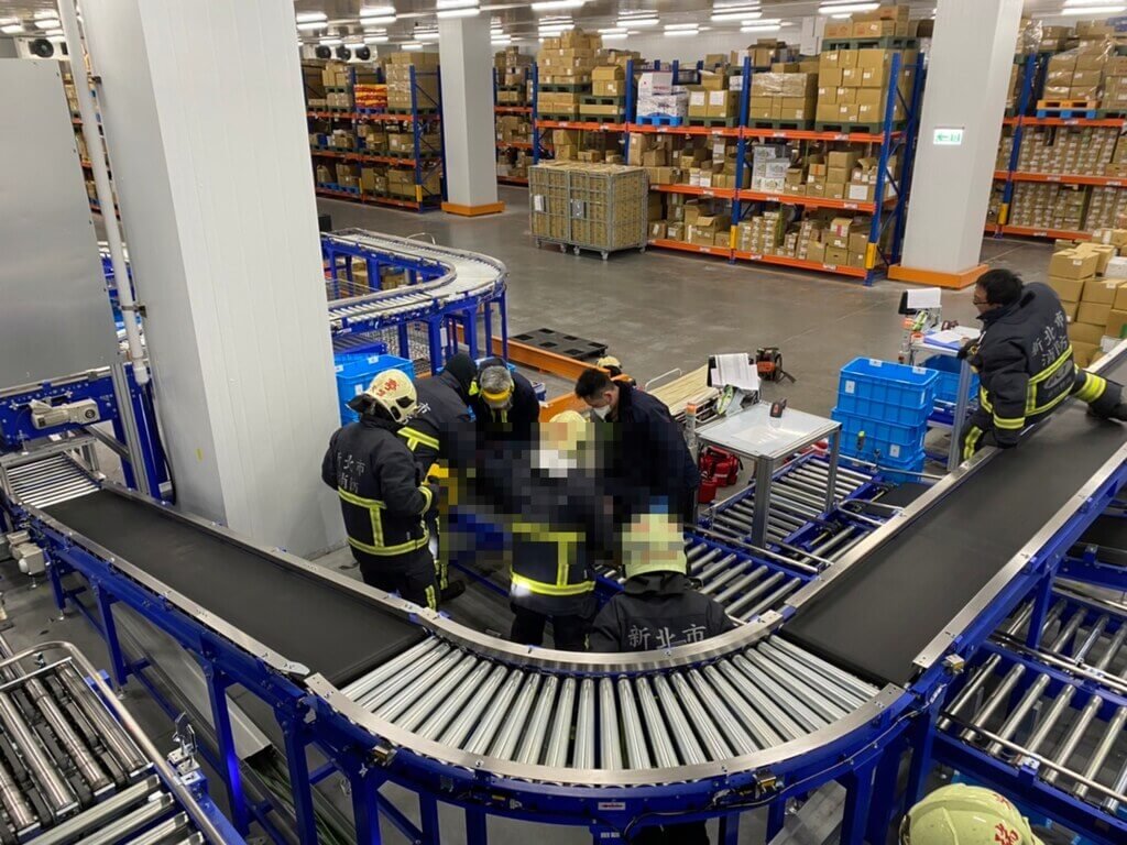 ▲新北市瑞芳區一間物流公司昨（13）晚深夜發生一起嚴重工安意外，男員工在維修冷凍庫的輸送帶時，疑似因沒有注意到後方升降機已啟動，遭到升降機撞擊後陷入昏迷，人卡在輸送帶中，送醫急救後不治。（圖／翻攝畫面）