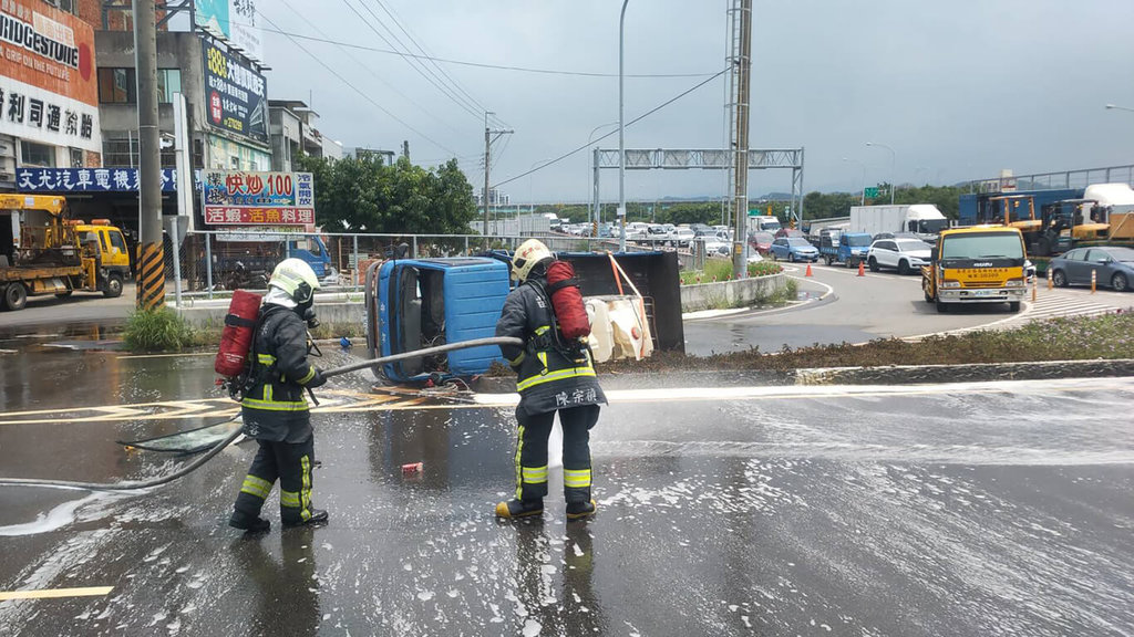 ▲一輛載著數桶硫酸的小貨車27日行經苗栗縣頭份市苗124甲線欲右轉中華路時不慎側翻，因硫酸液體大量外洩潑灑至路面，消防隊在現場灑水稀釋。（圖/中央社）
