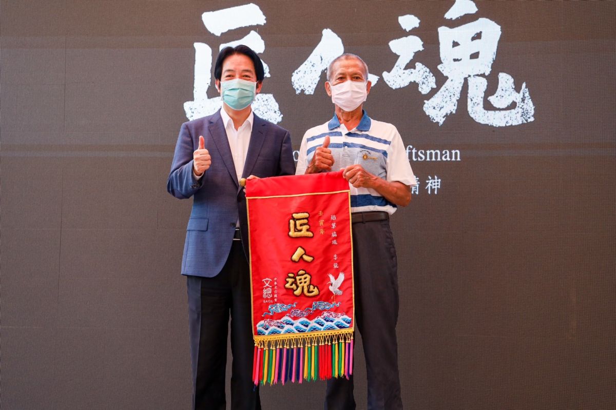 ▲賴清德頒發錦旗致贈全心奉獻精力的李龍，象徵李龍對草編工藝的「一生懸命」。（圖／周春米辦公室提供）