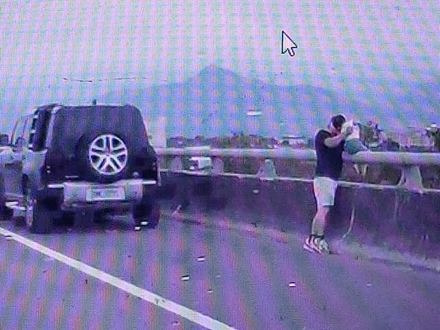 ▲有網友將行車紀錄器PO上網，影片中只見一名男子把車停在高速公路路肩，並抱著一名幼童坐上護欄。（圖／翻攝臉書爆怨公社）