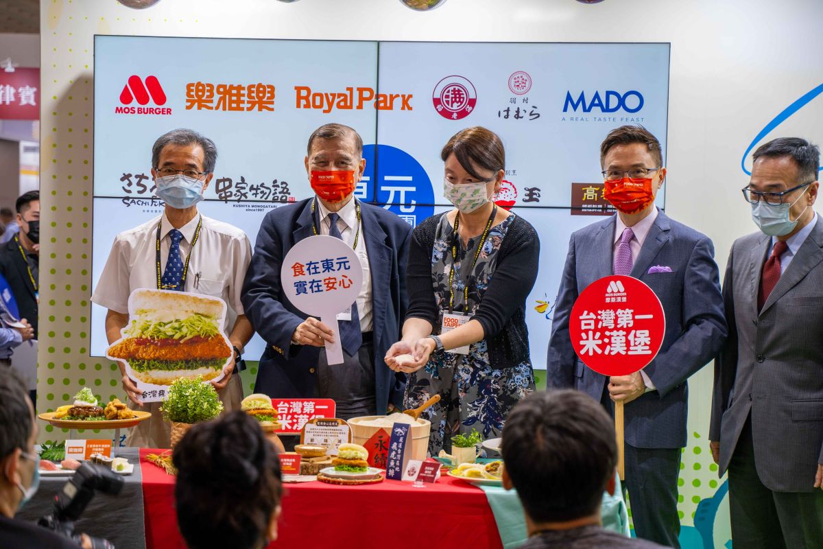 ▲東元黃茂雄會長（左二）手持「食在東元實在安心」標語牌，出席台北國際美食展開幕（右二為外貿協會黃志芳董事長）。（圖／東元提供）