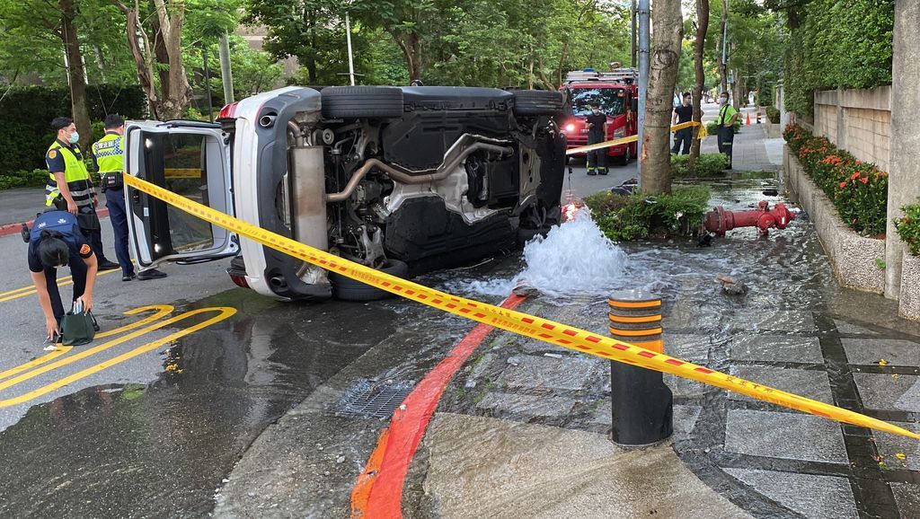 ▲北市一名婦人，27日清晨開車自撞消防栓後，導致車身90度翻車，旁邊消防用水也跟著大量湧出。（圖／翻攝畫面）