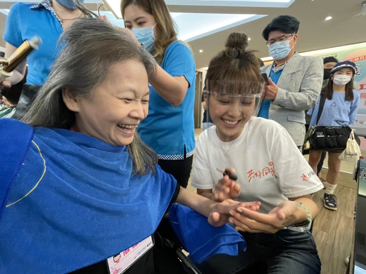 ▲伊甸公益大使大元(林艾璇)細心的為身障朋友擦指甲油，兩人露出開心笑容（圖／記者林怡孜攝，2022,07,06）